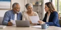 An older couple reviewing blank Medicare coverage comparison papers with an insurance professional